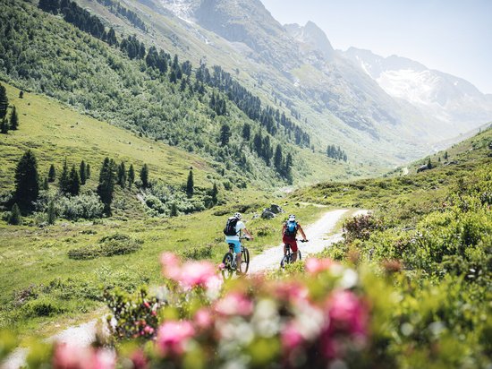 St. Anton: Sommerurlaub, Winterspaß Zwei Radfahrer auf einem Bergweg in einer grünen Alpenlandschaft