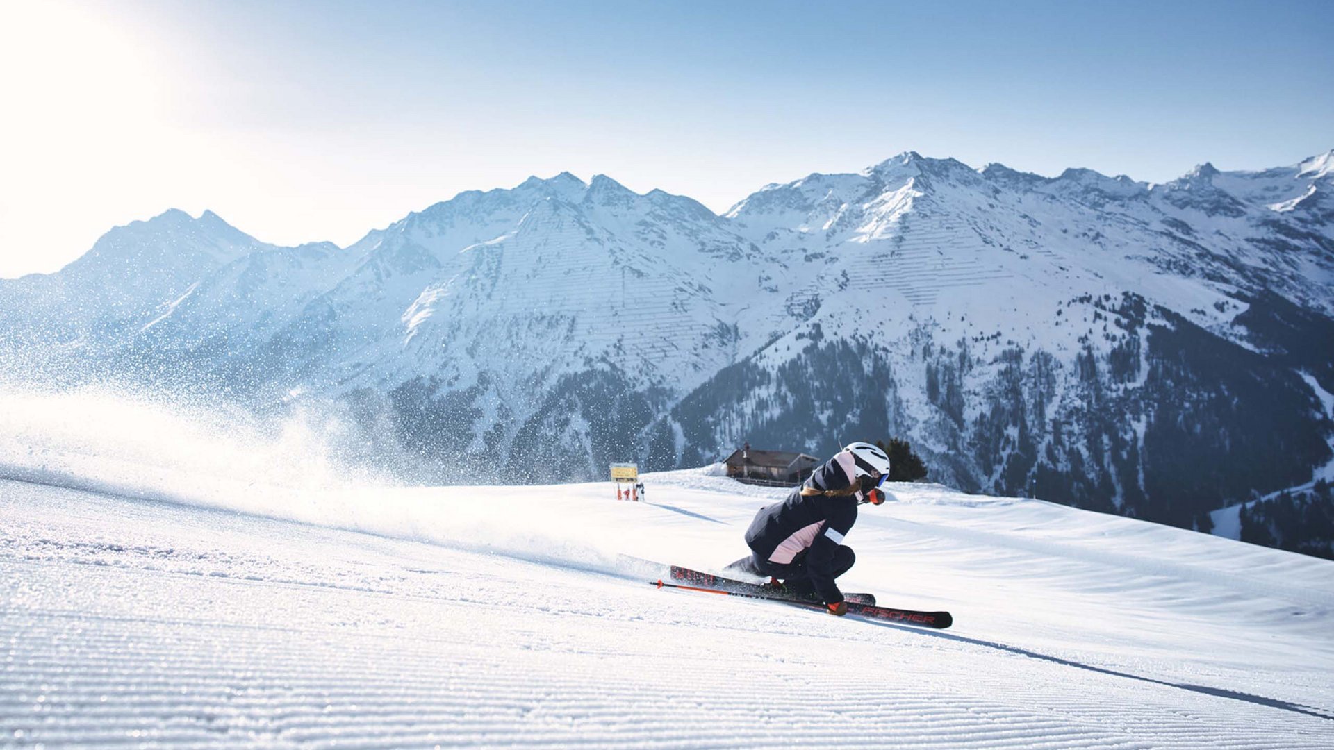 There’s nowhere more wonderful for winter holidays! Skier on groomed slope with snowy mountains in the background