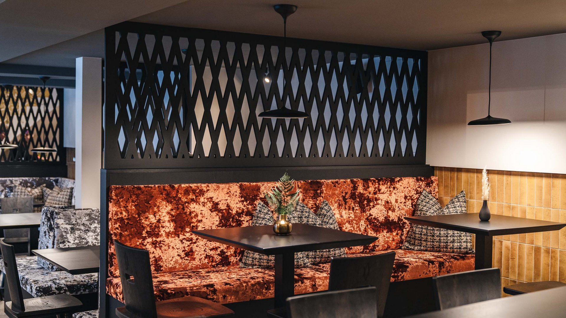 Modern café corner with orange velvet sofa and black tables