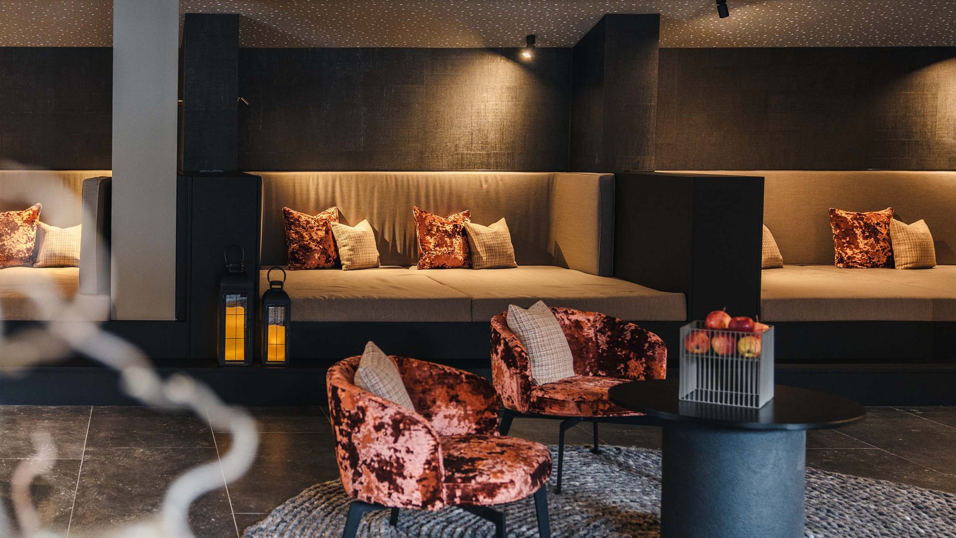 Modern lounge with velvet chairs and large sofas in warm ambient lighting