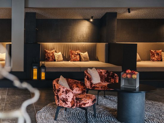 Modern lounge with velvet chairs and large sofas in warm ambient lighting