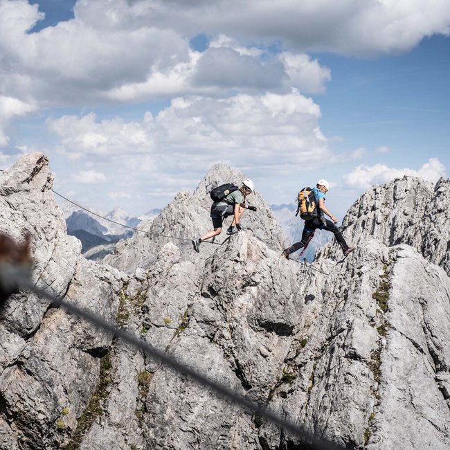 Ihr Urlaub am Arlberg im Sommer – das Wanderparadies Zwei Kletterer wandern durch felsiges Gebirge bei klarem Himmel