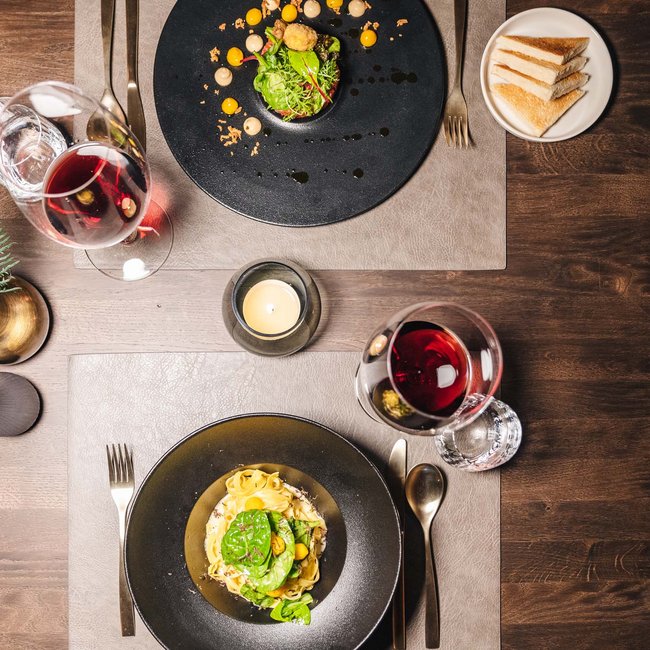 zwei teller mit feinem essen, weingläser und brotscheiben auf holztisch