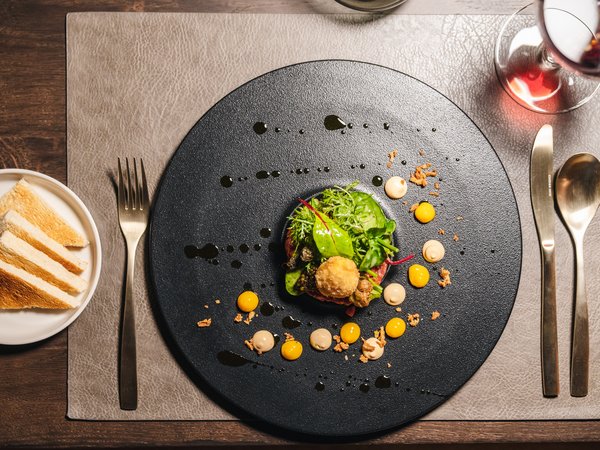 3 restaurants under one roof Elegant appetizer on black plate with sauces and toasted bread slices