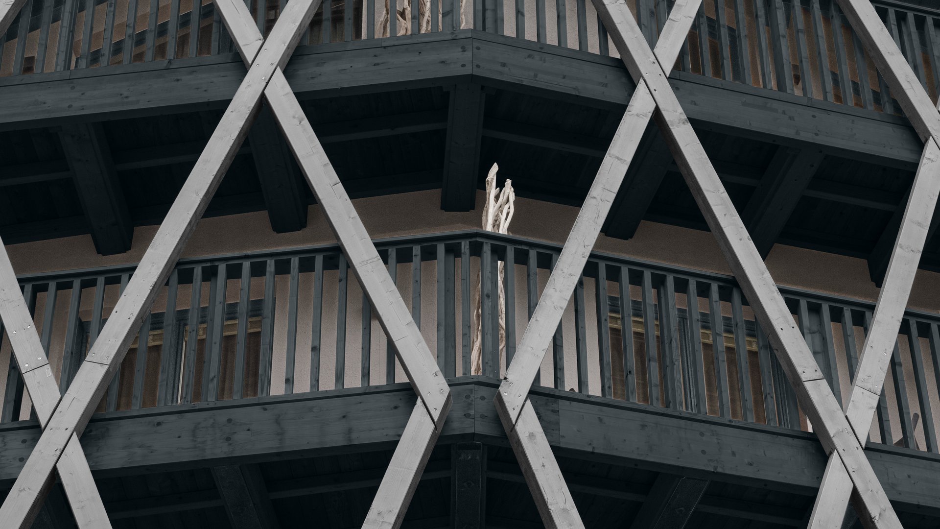 Fassade eines Hauses mit markanten diagonalen Holzbalken und Balkonen