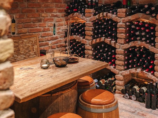 Wine cellar with rustic wooden table and wine bottles on brick shelves