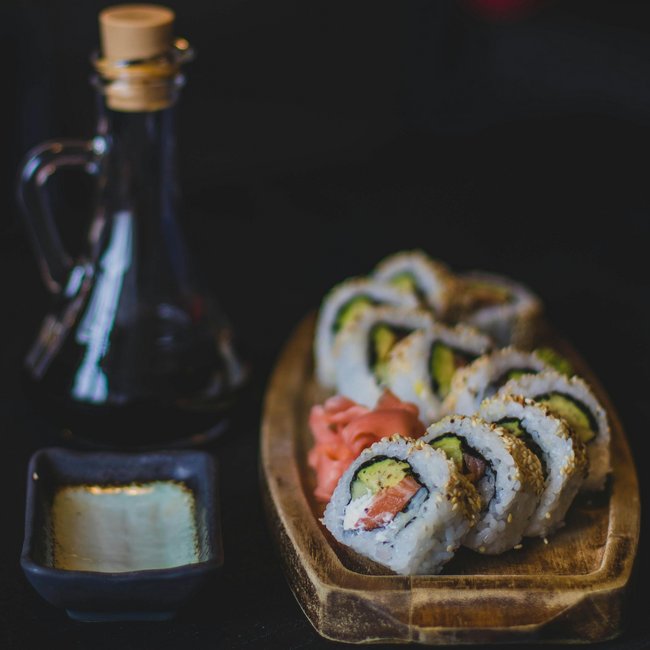 3 Restaurant unter einem Dach Sushi-Rollen mit Avocado und Lachs auf Holzbrett mit Sojasauce und Ingwer