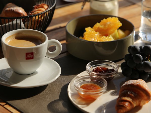 Coffee, croissant, jams, grapes, and fruit salad on wooden table