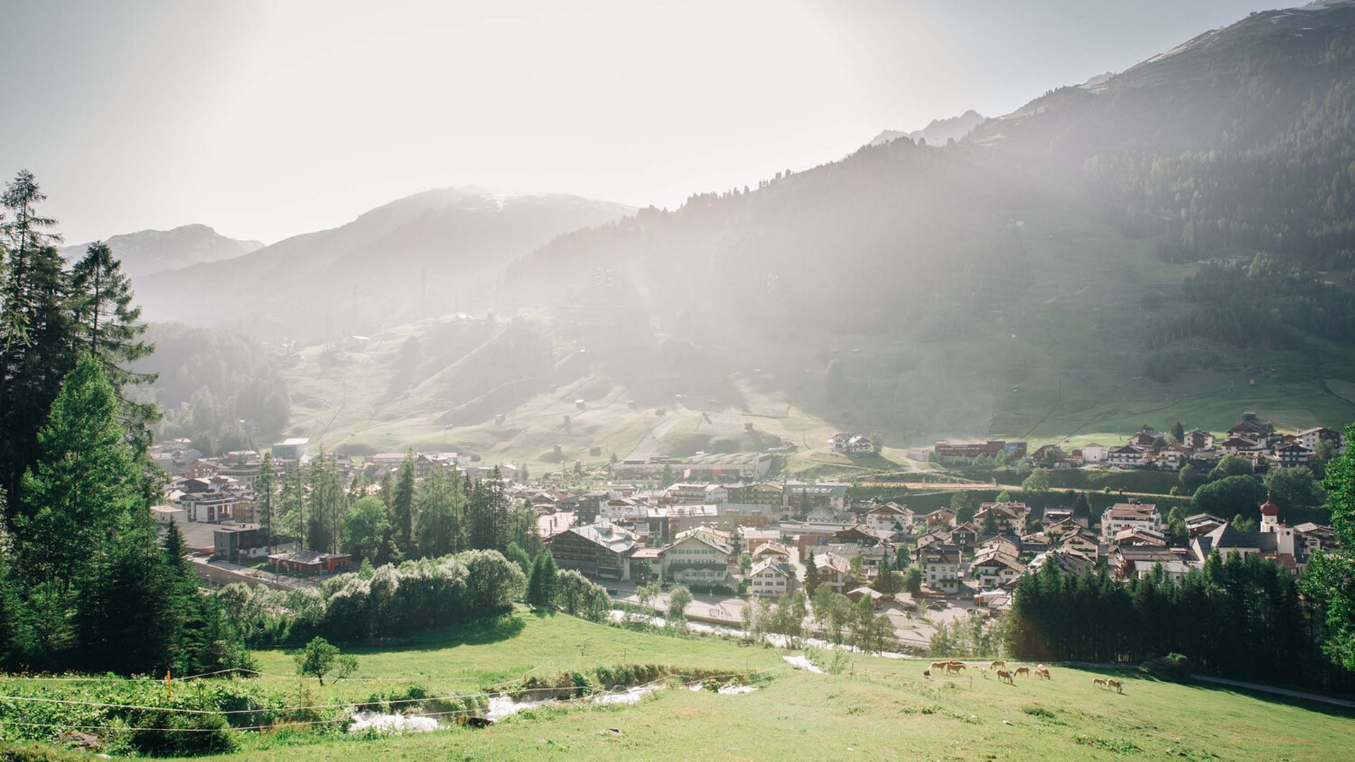 Village in green valley with misty mountains in the background