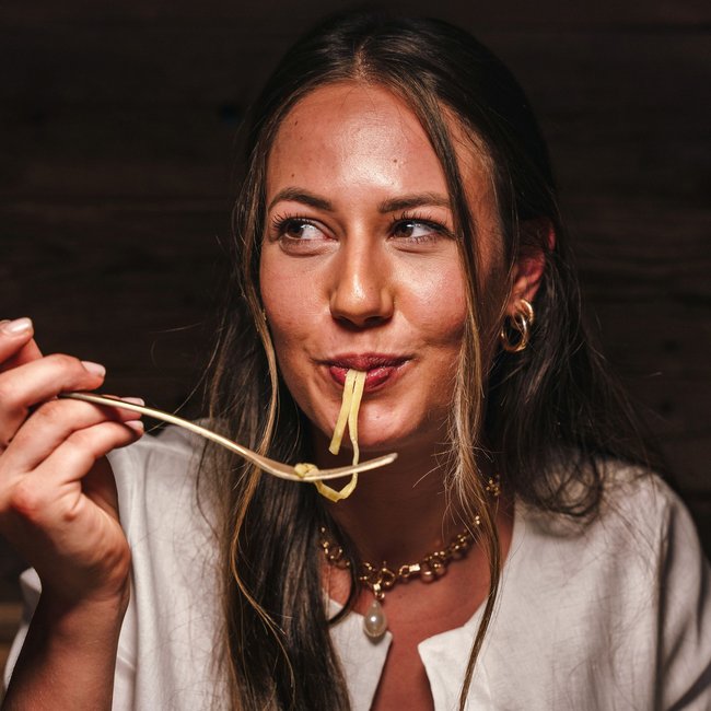 Frau isst genussvoll Nudeln mit Gabel