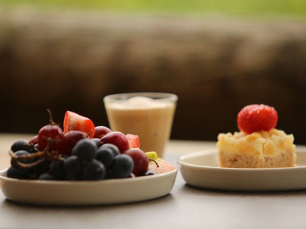 Plate with grapes, cake topped with strawberry, and a glass of coffee