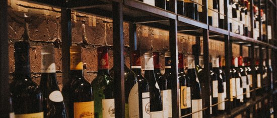 3 restaurants under one roof Shelf with many wine bottles in front of brick wall