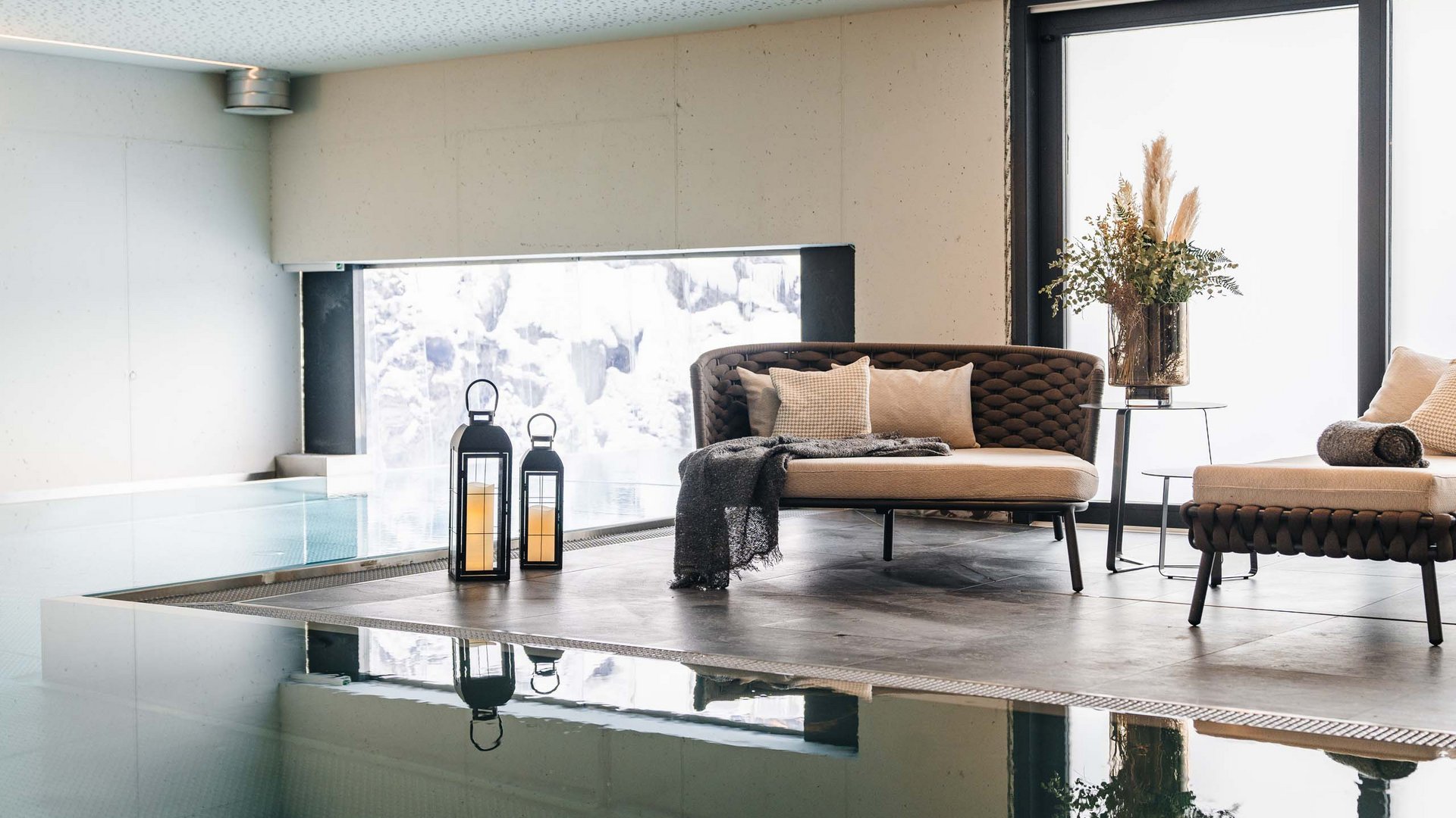 Modern lounge with sofas, lanterns, and view of indoor pool