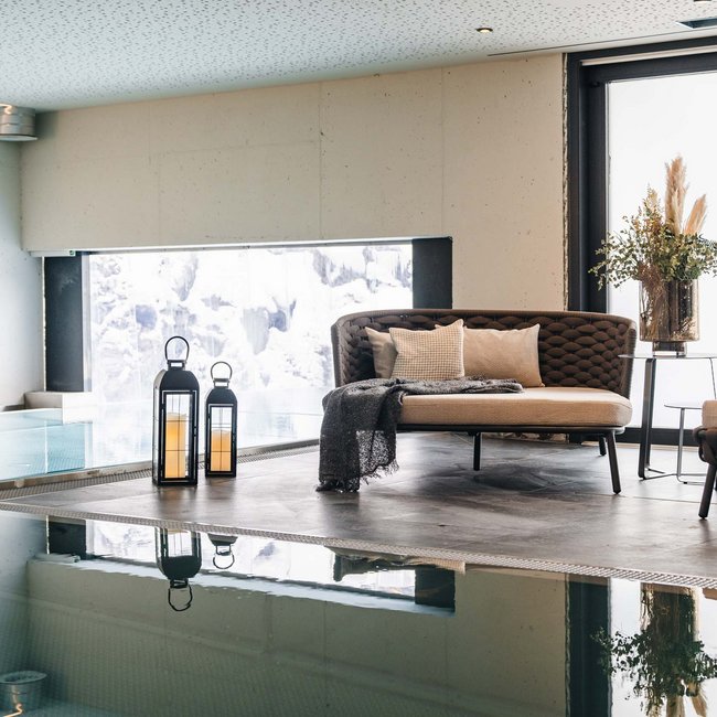 Moderne Lounge mit Sofas, Kerzenlaternen und Blick auf Innenpool