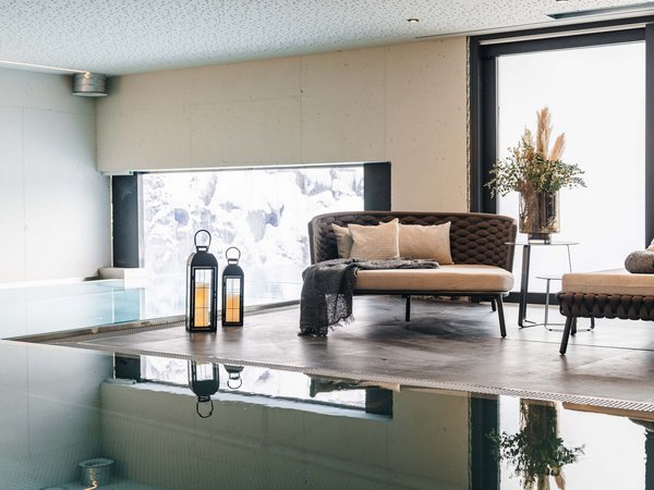 Moderne Lounge mit Sofas, Kerzenlaternen und Blick auf Innenpool