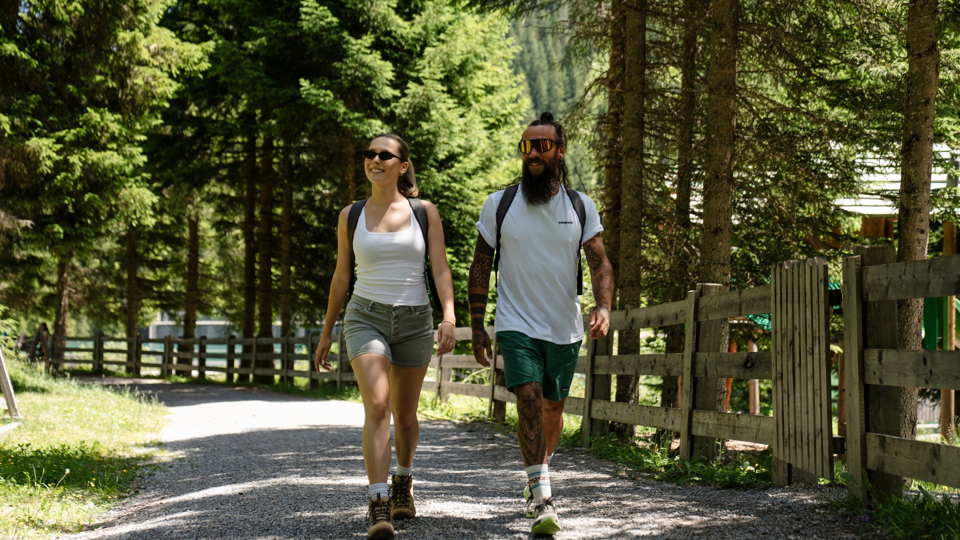 Junges Paar mit Rucksäcken wandert auf einem Waldweg bei Sonnenschein
