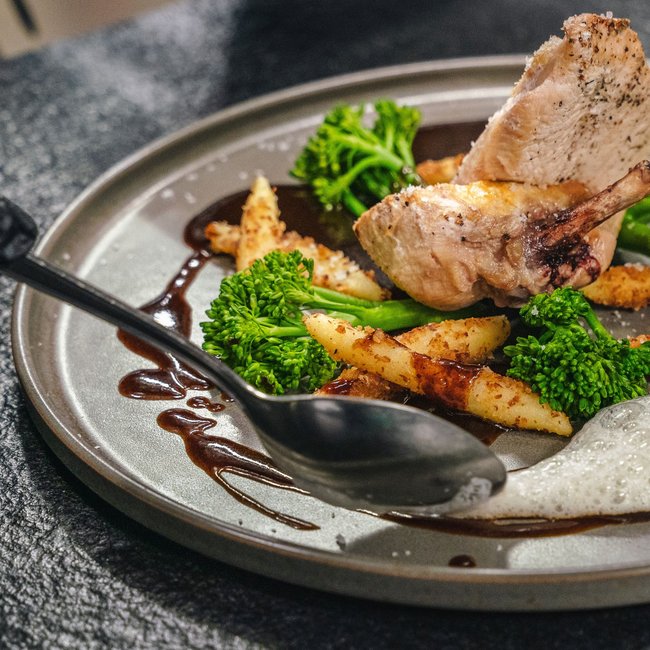 3 restaurants under one roof Poultry dish with asparagus, broccoli florets, and sauce on gray plate