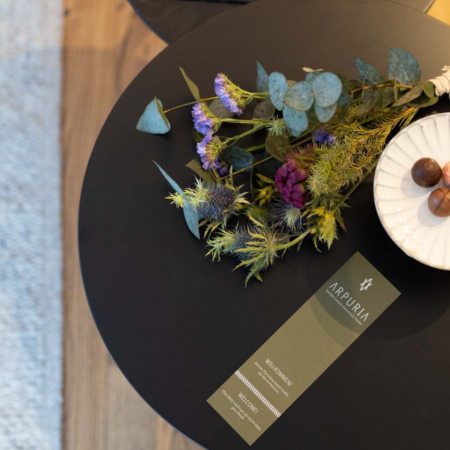 Tisch mit Blumenstrauß, Karte und Schale mit Pralinen