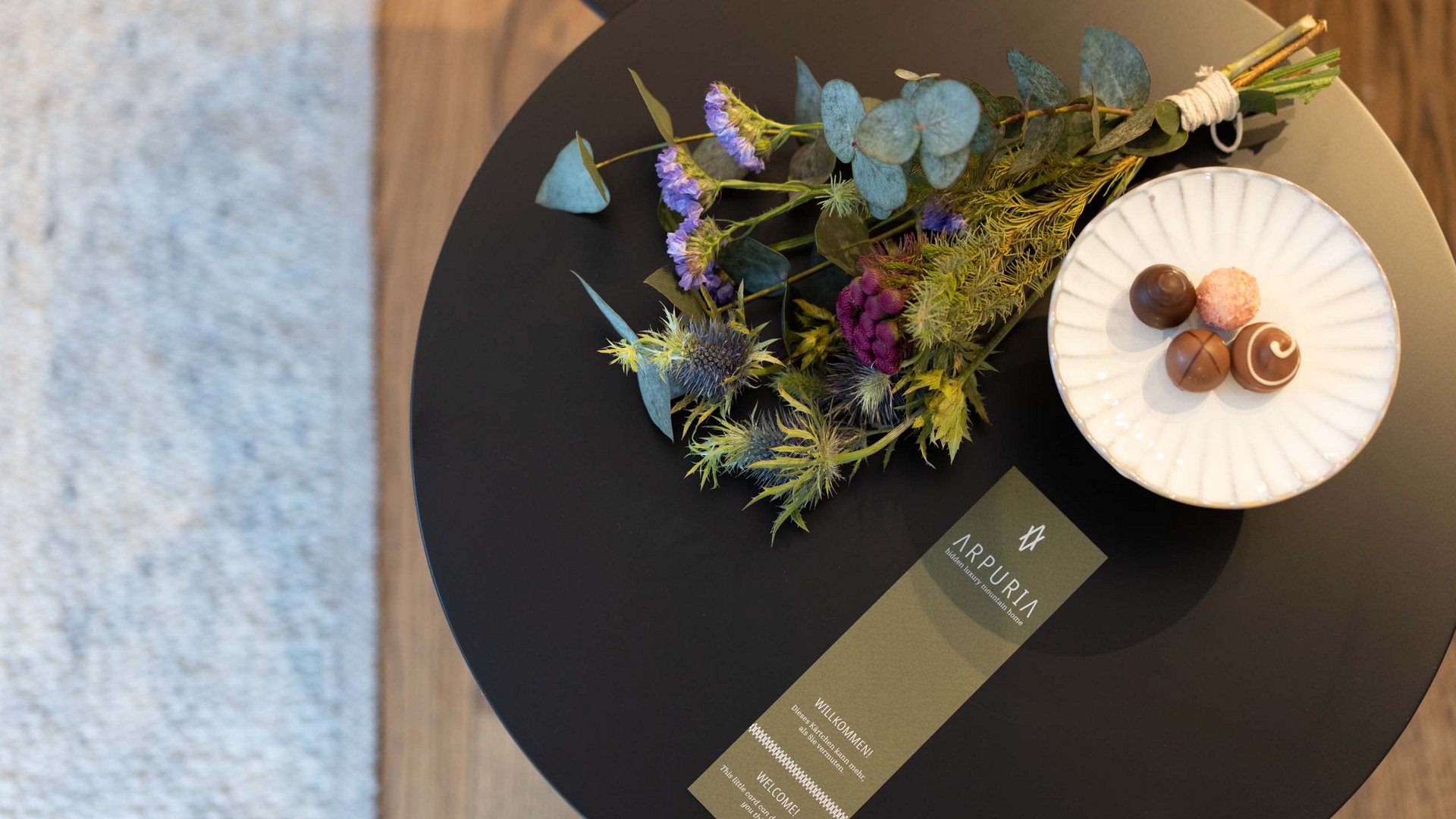 Table with flower bouquet, card, and bowl with chocolates