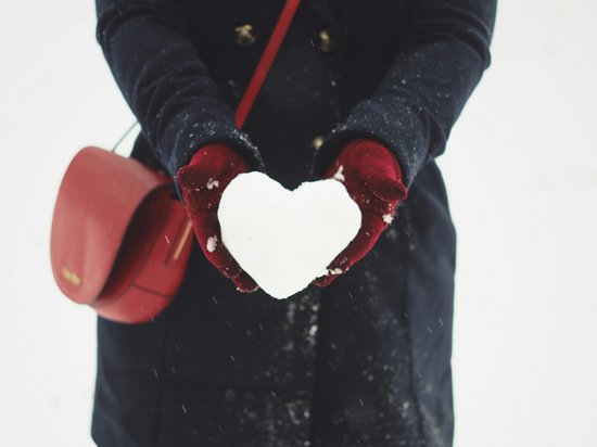 St. Anton: Sommerurlaub, Winterspaß Person hält herzförmigen Schneeball mit roten Handschuhen