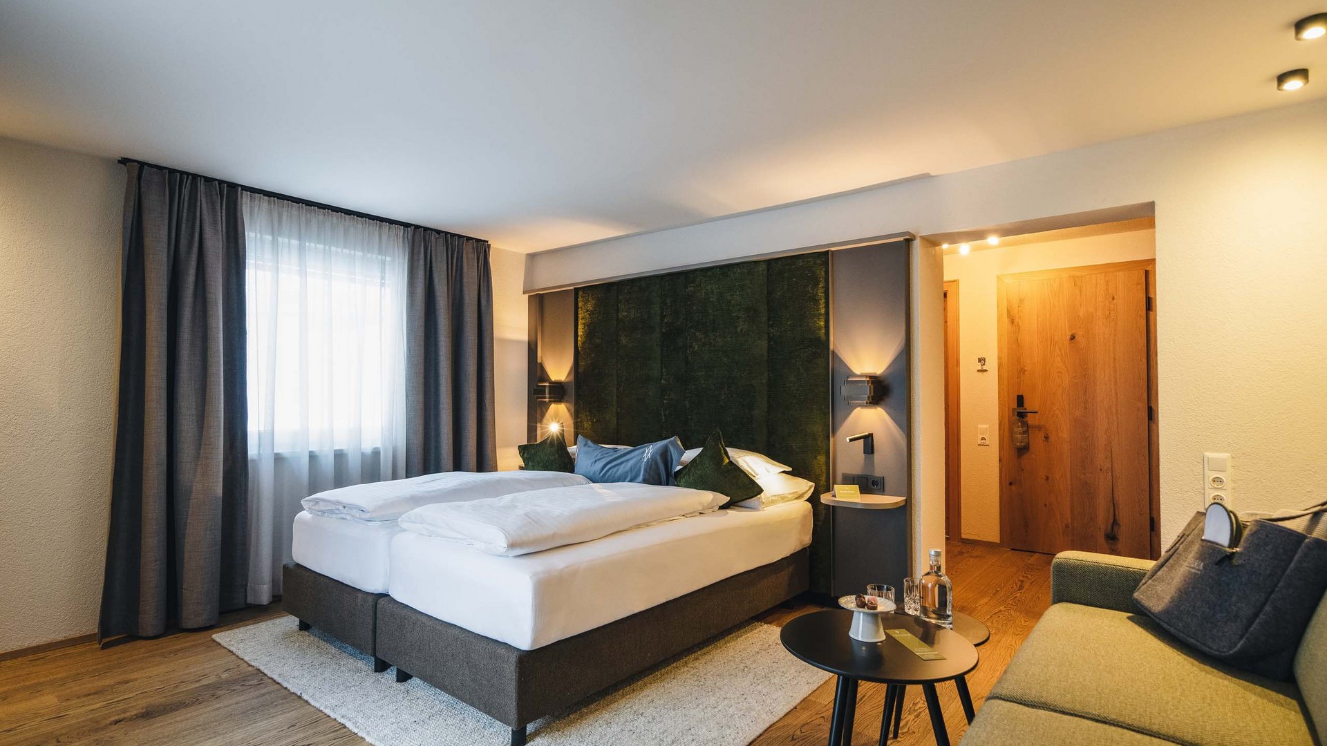 Modern hotel room with double bed, sofa, and cozy lighting