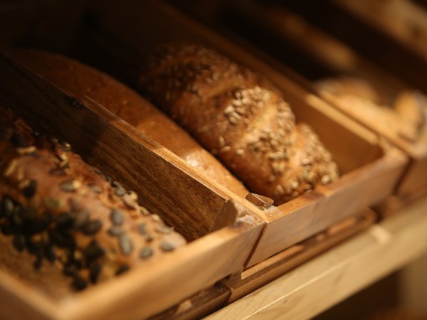 Various seeded breads in wooden trays on a shelf