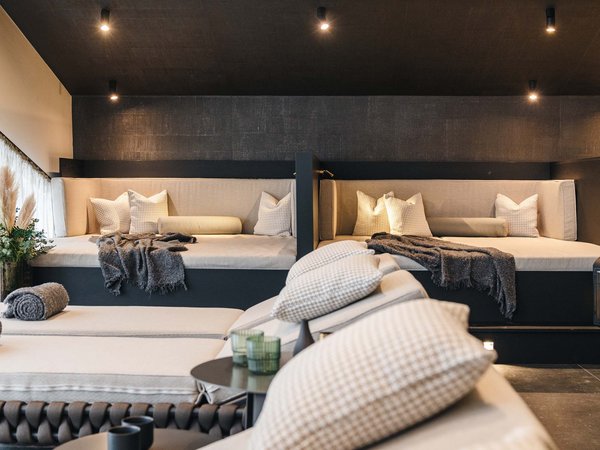 Welcome to your holiday on Arlberg – in summer and winter Cozy lounge area with beige seating and decorative pillows under soft lighting