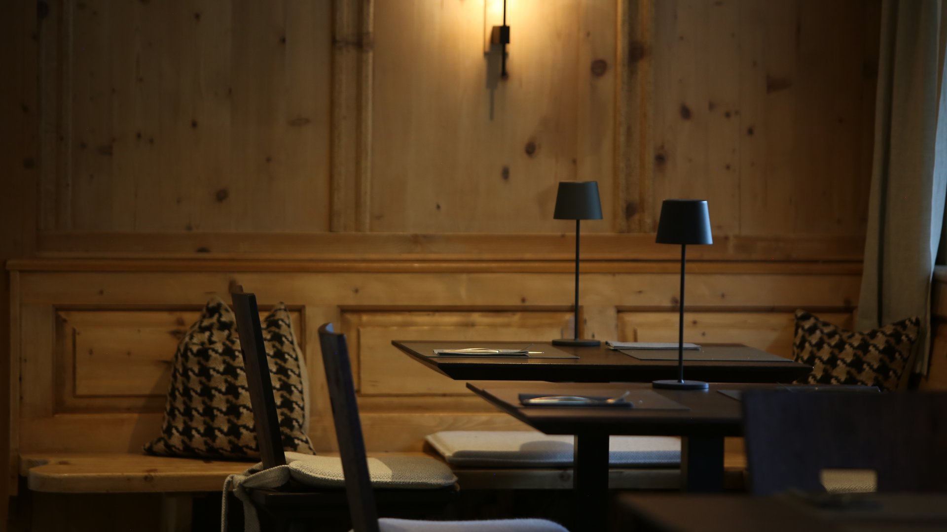 Gemütliche Holzecke mit Tischlampen und gepolsterten Stühlen in Restaurant