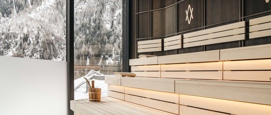 Moderne Sauna mit Blick auf schneebedeckte Berge durch großes Fenster