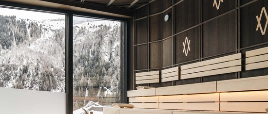 Moderne Sauna mit Blick auf schneebedeckte Berge durch großes Fenster