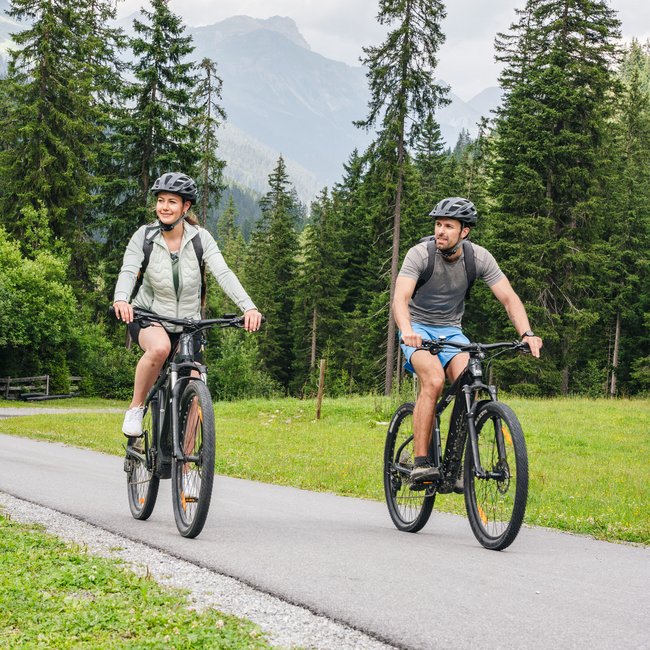 Ihr Bikeurlaub in Tirol Zwei Radfahrer fahren auf einem Weg durch einen bewaldeten Bergpark