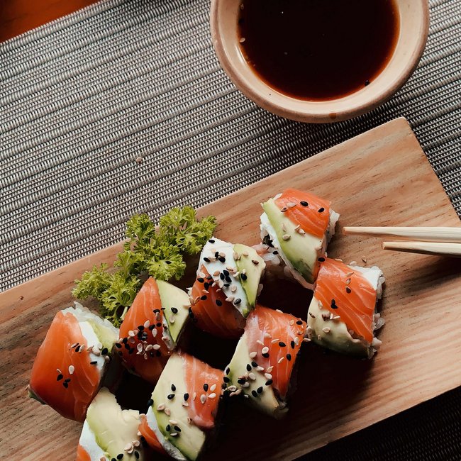 Salmon and avocado sushi on wooden board with soy sauce