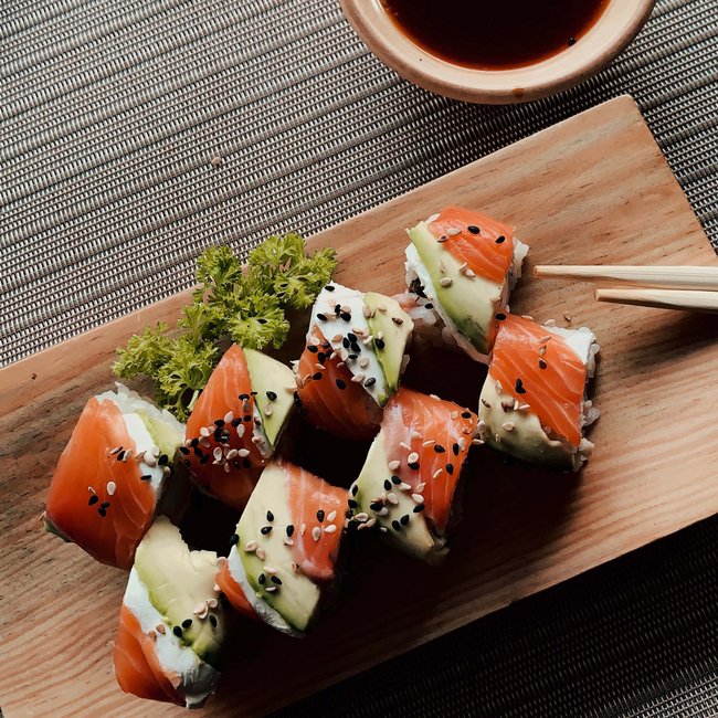 Kulinarische Genüsse im Arpuria Sushi mit Lachs und Avocado auf Holzbrett mit Sojasauce