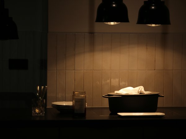 Kitchen counter with black pot covered by cloth under hanging lamps