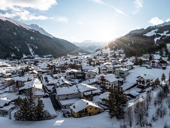 Sonnenaufgang über verschneitem Bergdorf im Tal zwischen Bergen