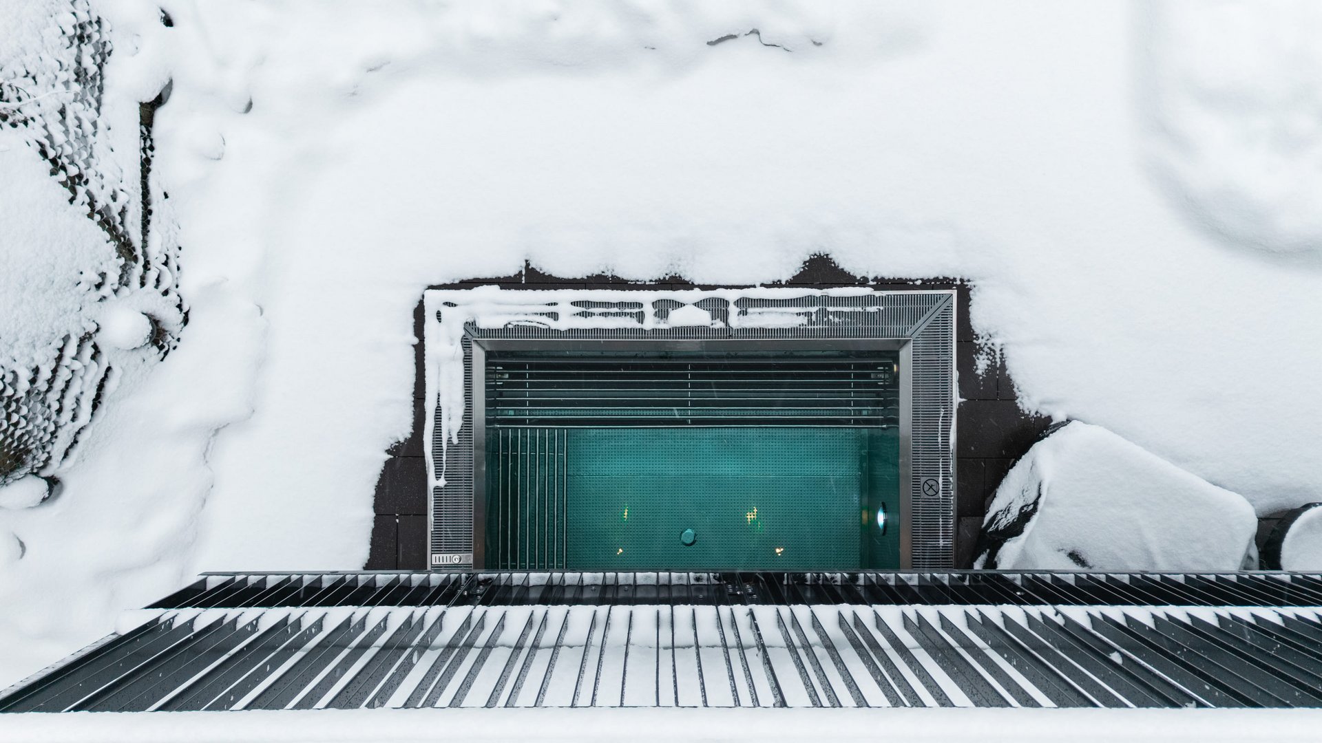 Top view of a heated swimming pool surrounded by snow