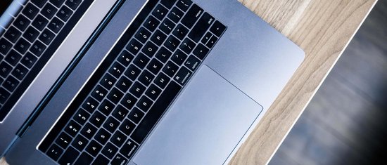 Offener Laptop auf hellem Holzschreibtisch von oben fotografiert