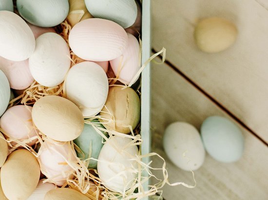 St. Anton: Sommerurlaub, Winterspaß Pastellfarbene Eier in einer Holzkiste mit Stroh auf Holzoberfläche