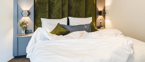 Modernes Schlafzimmer mit grünem Kopfteil und weißer Bettwäsche