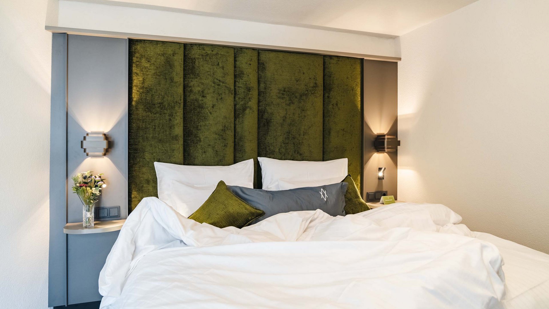 Modern bedroom with green headboard and white bed linens