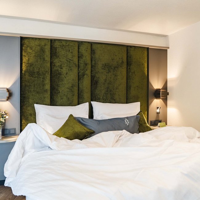 Modernes Schlafzimmer mit grünem Kopfteil und weißer Bettwäsche