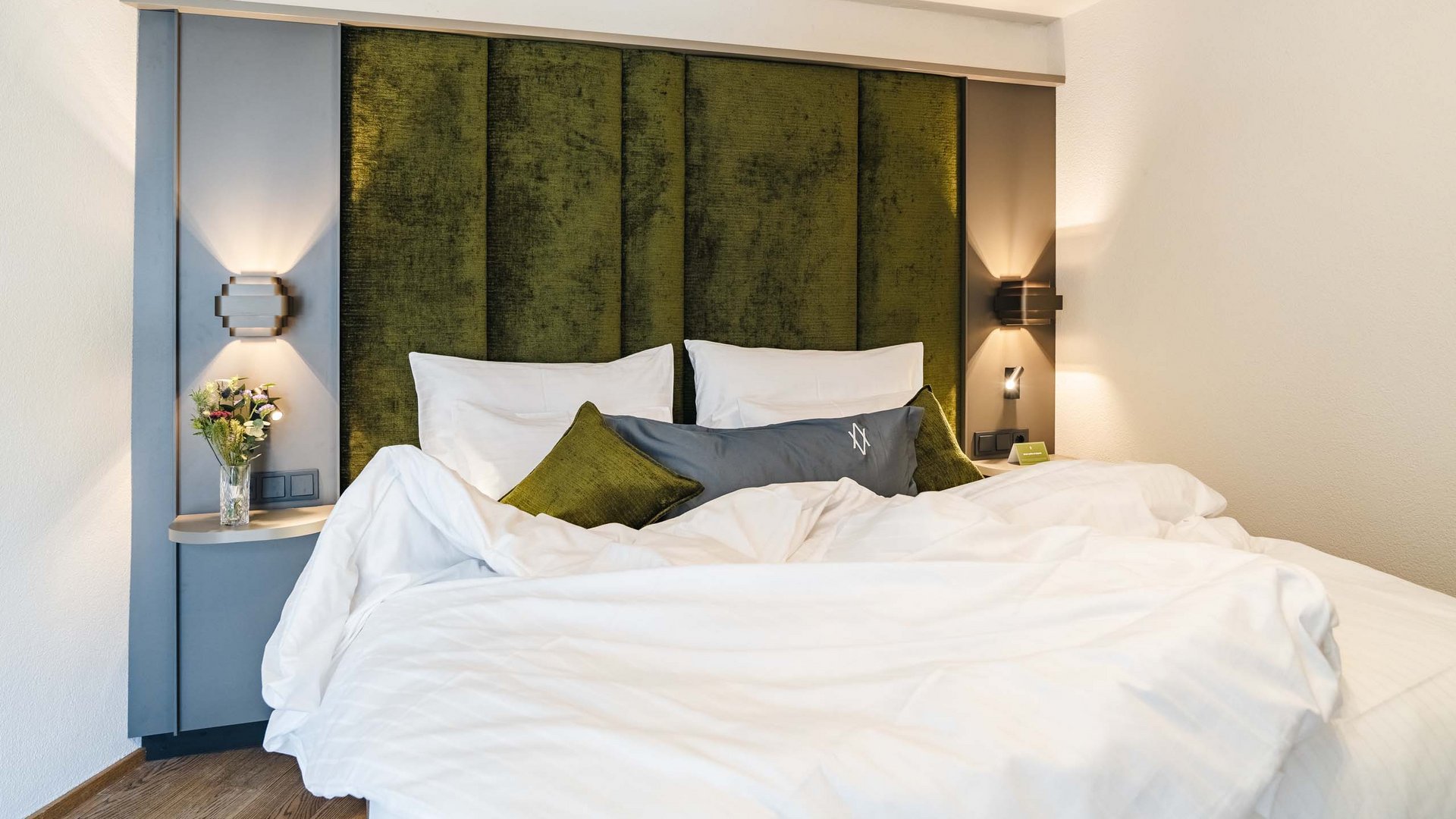 Modernes Schlafzimmer mit grünem Kopfteil und weißer Bettwäsche