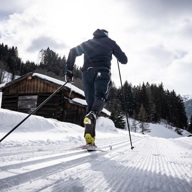 Cross-country skier on groomed trail in snowy alpine landscape