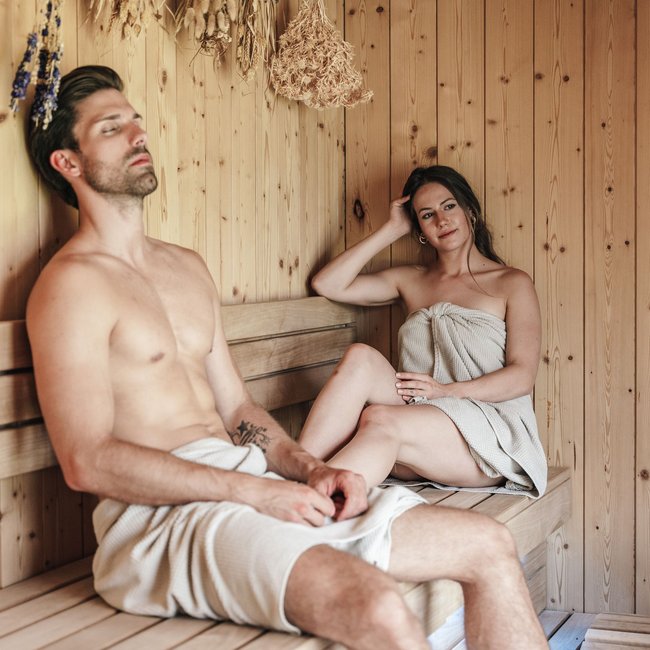 Welcome to your holiday on Arlberg – in summer and winter Man and woman relaxing in a wooden sauna