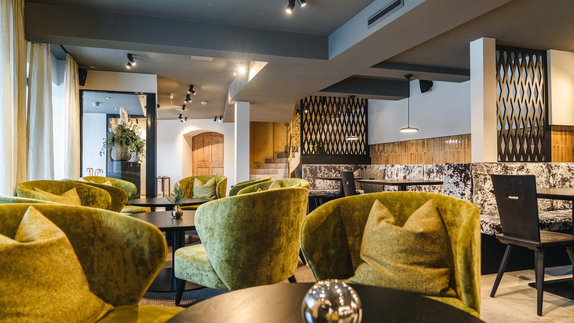 Modern café with green velvet chairs and round black tables