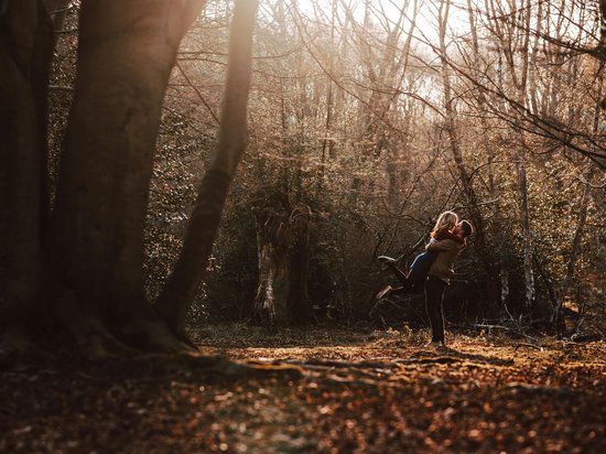 St. Anton: Sommerurlaub, Winterspaß Paar umarmt sich glücklich im herbstlichen Wald im Sonnenlicht