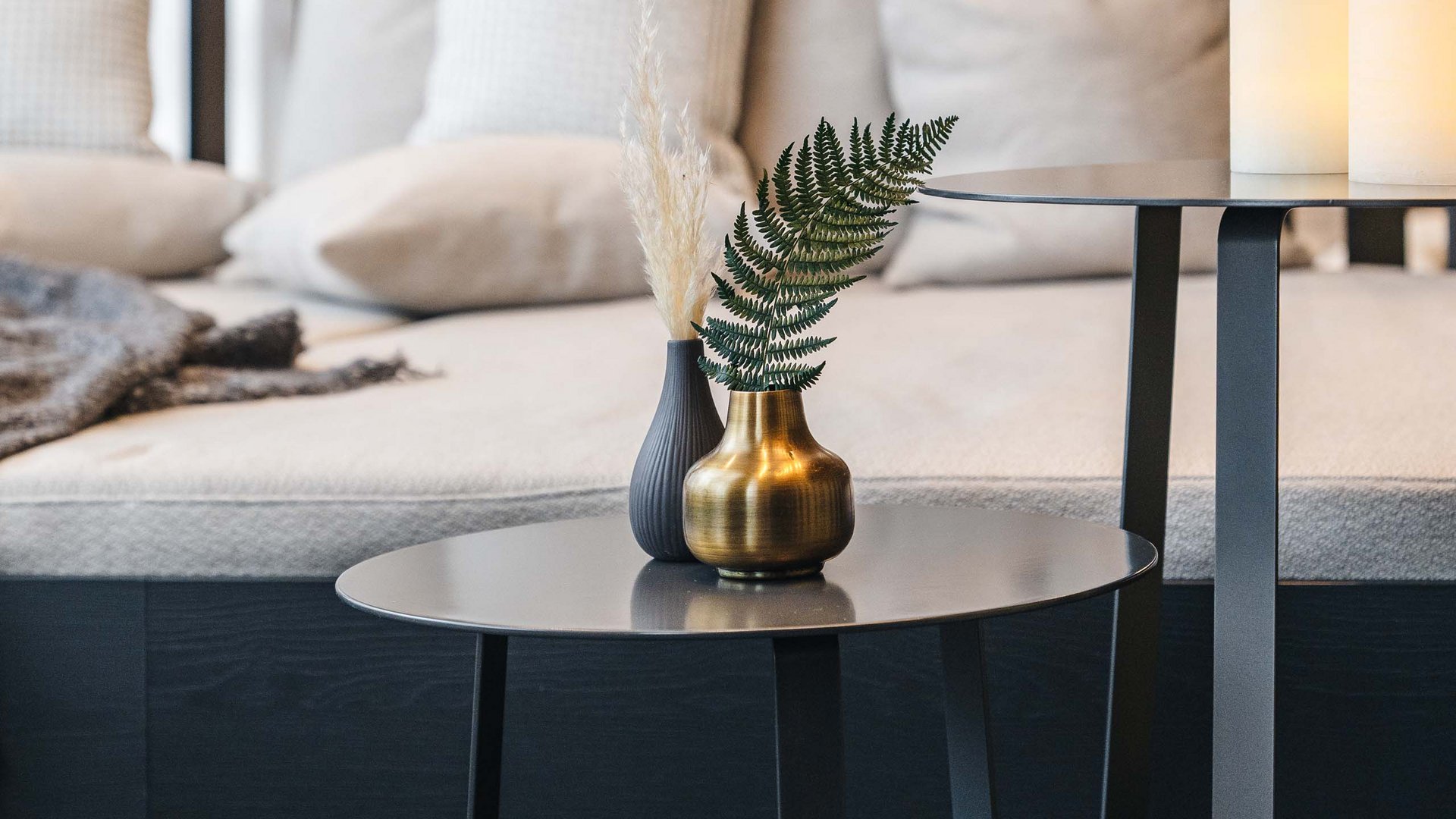 Modern coffee table with vases and sofa cushions in background