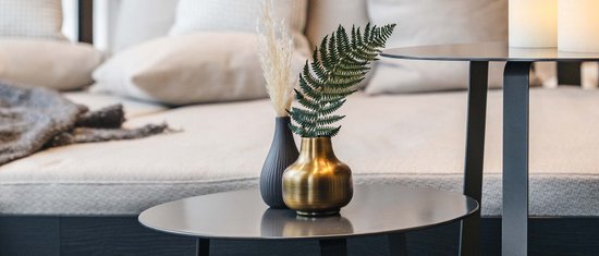 Modern coffee table with vases and sofa cushions in background