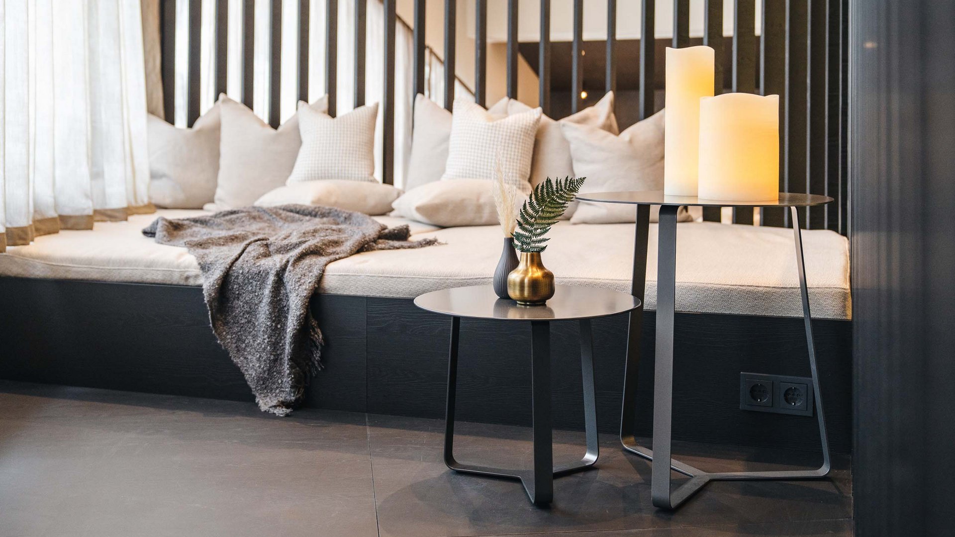 Cozy seating area with pillows, blanket, candles, and modern side tables