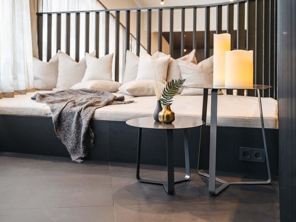 Welcome to your holiday on Arlberg – in summer and winter Cozy seating area with pillows, blanket, candles, and modern side tables